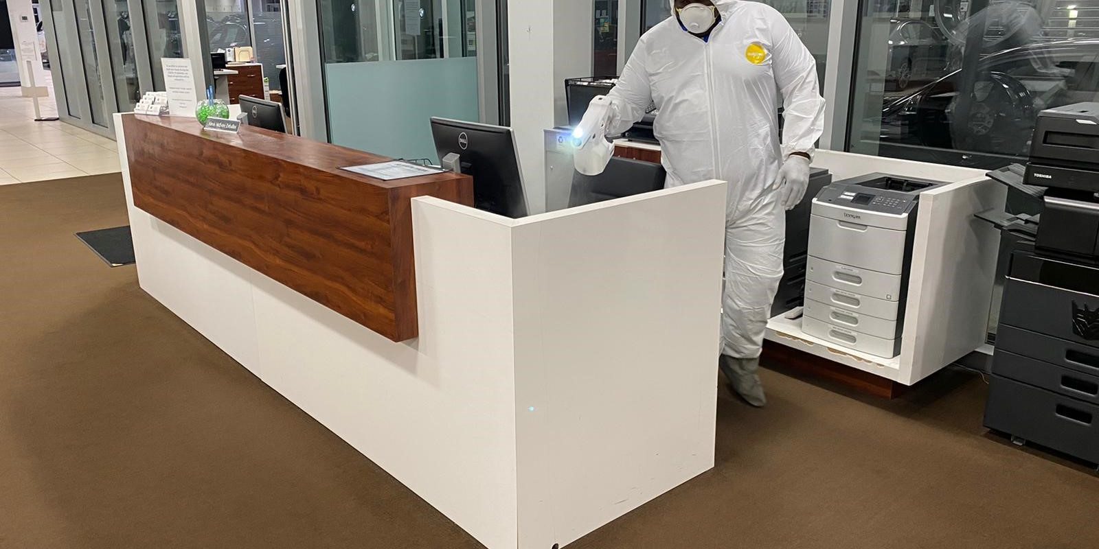 disinfect Man in hazmat suit spraying down desk