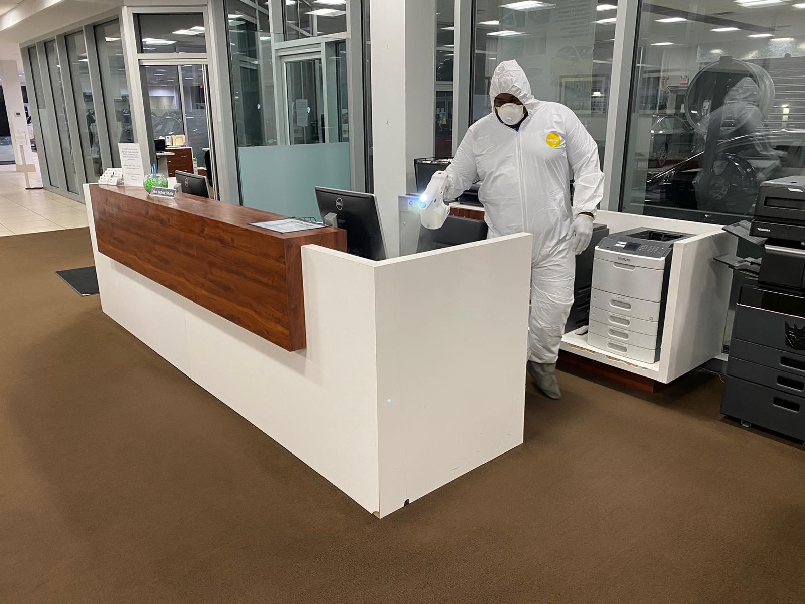 Man in hazmat suit spraying down desk