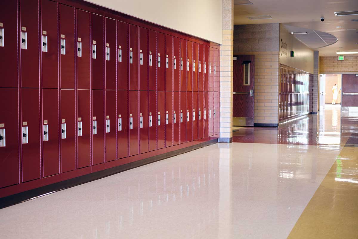 An empty school hallway with rows of red lockers and clean, shiny floors.