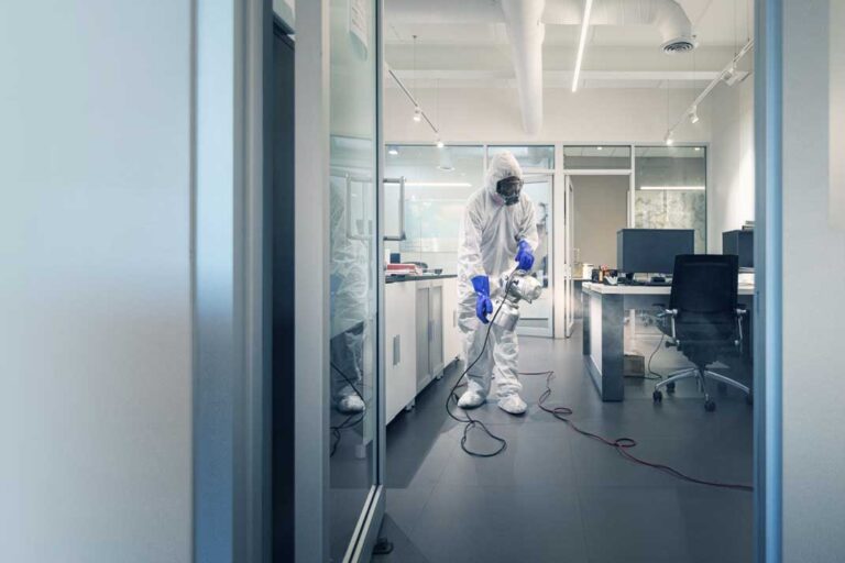 Man spraying a disinfectant inside of an office.