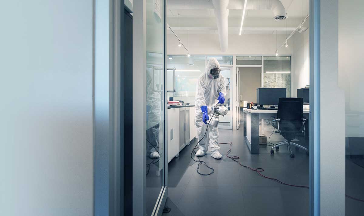 Man spraying a disinfectant inside of an office.