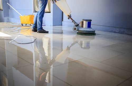 A building maintenance man using a floor polisher while cleaning tile floor
