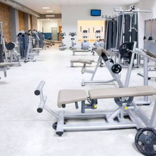 Inside a brightly lit gym with multiple workout equipment.