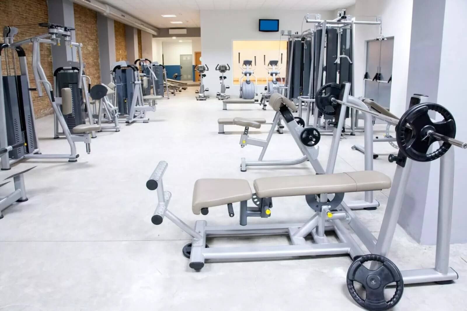 Inside a brightly lit gym with multiple workout equipment.