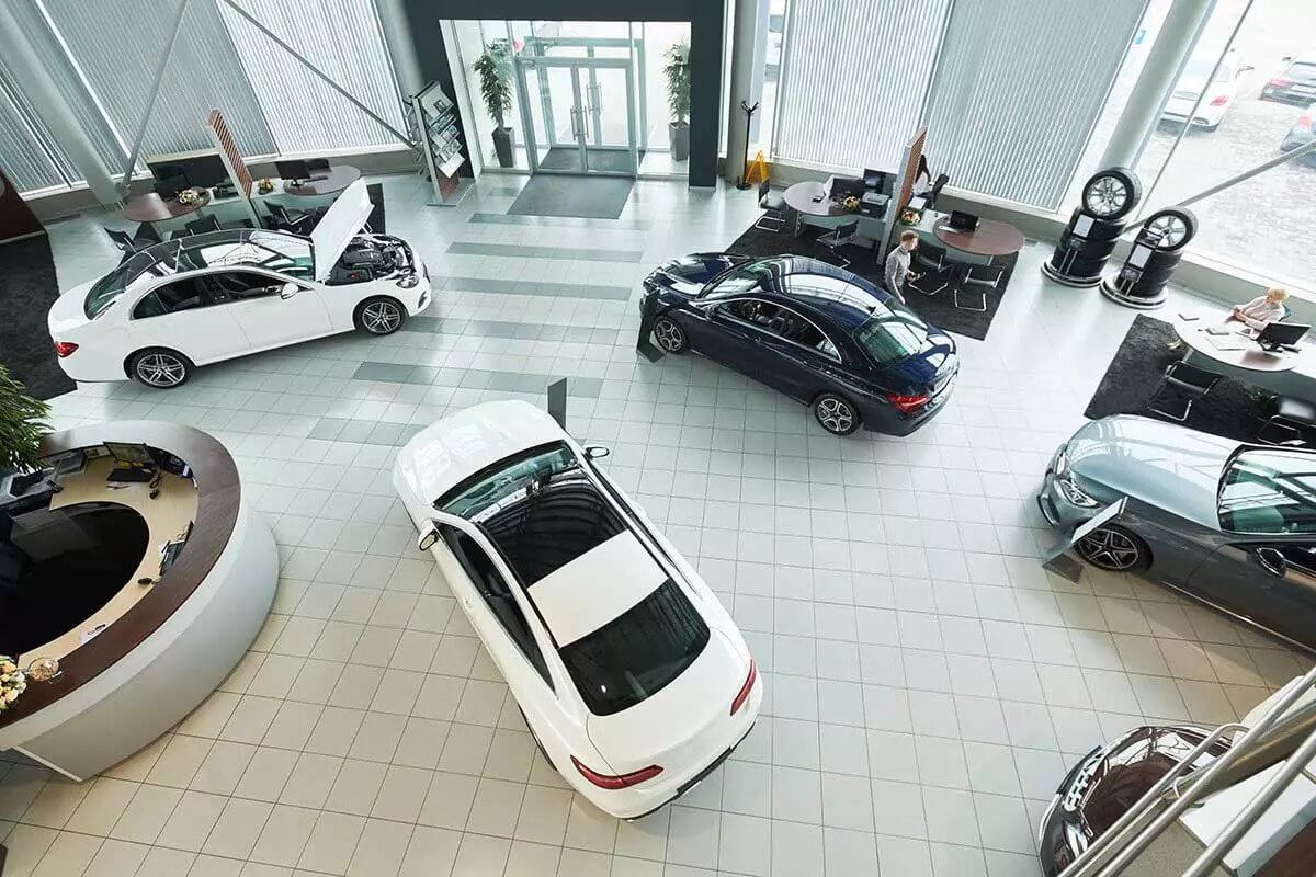 Multiple cars inside a large car dealership.