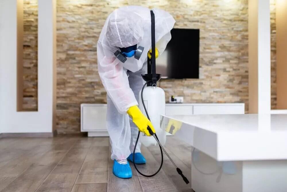 A worker using a spray cleaner to clean a table inside a lounge.